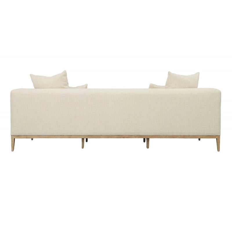 Canapé beige capitonné avec quatre coussins